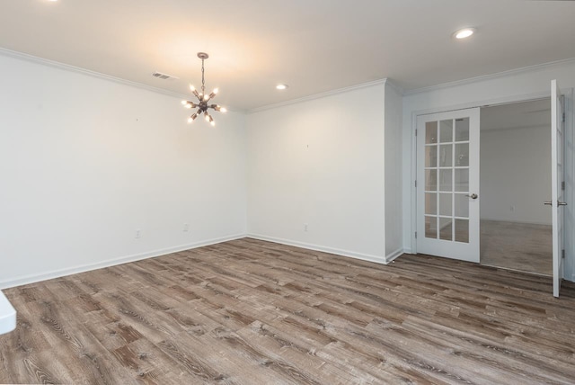 empty room with wood finished floors, visible vents, and crown molding