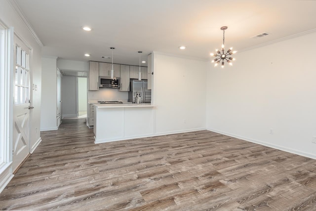 kitchen with wood finished floors, visible vents, light countertops, ornamental molding, and appliances with stainless steel finishes