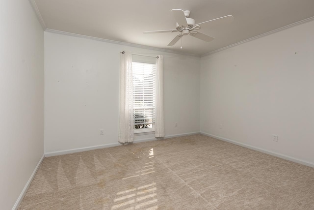 spare room featuring carpet floors, ornamental molding, a ceiling fan, and baseboards