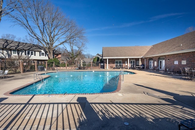 pool with a patio area and fence