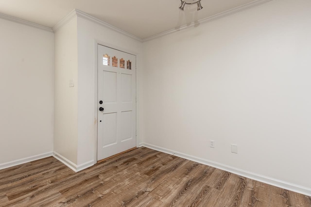 empty room with ornamental molding, wood finished floors, and baseboards