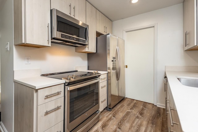 kitchen featuring a sink, appliances with stainless steel finishes, dark wood finished floors, and light countertops