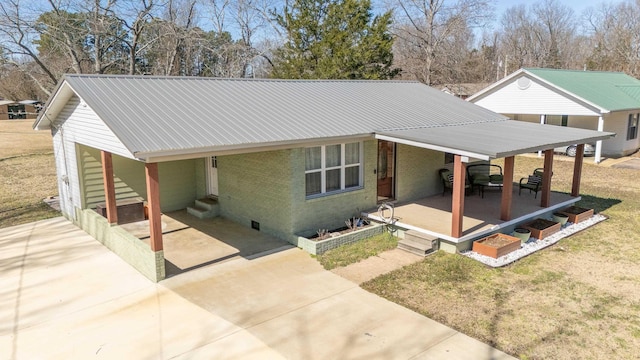 view of front of property with driveway, brick siding, metal roof, an attached carport, and a front yard