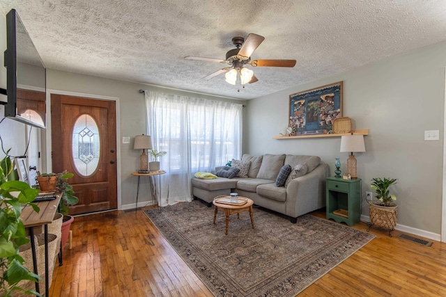 living room with baseboards, visible vents, ceiling fan, and hardwood / wood-style floors