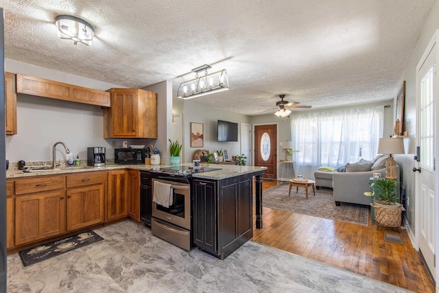 kitchen with electric range, brown cabinetry, open floor plan, a sink, and a peninsula