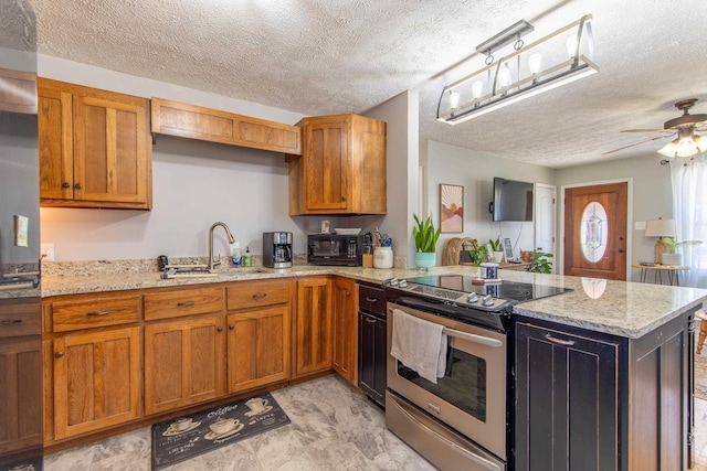 kitchen with brown cabinets, a peninsula, light stone countertops, stainless steel electric stove, and a sink