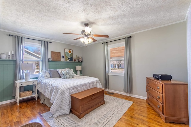 bedroom with light wood-style flooring, baseboards, ceiling fan, and crown molding