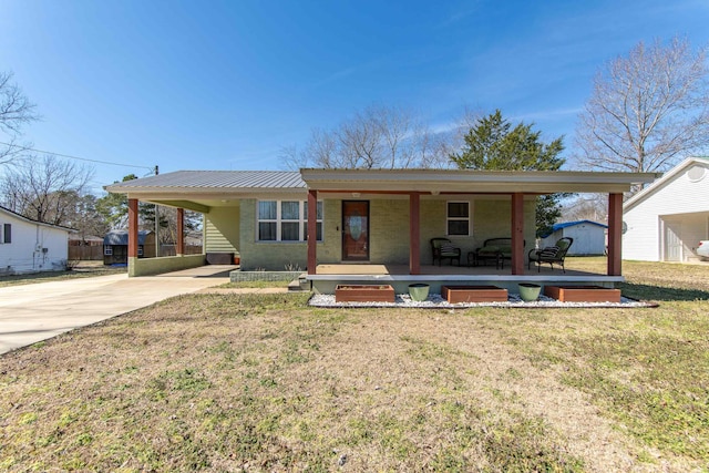 view of front of property with concrete driveway, metal roof, a porch, a carport, and a front yard