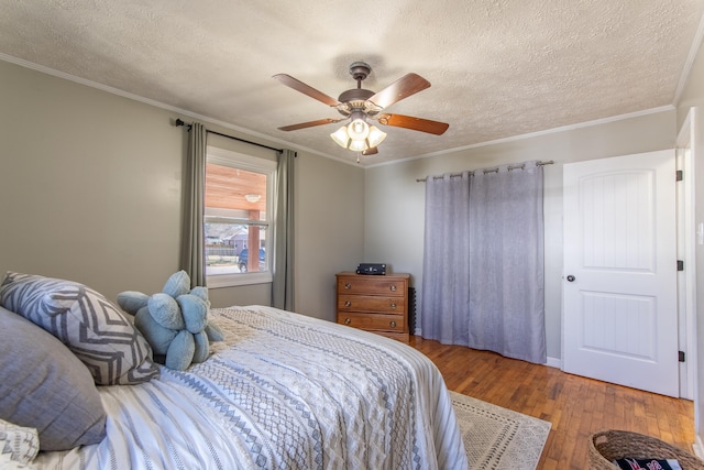 bedroom featuring a textured ceiling, ornamental molding, and wood finished floors