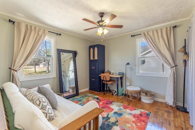 bedroom featuring crown molding, light wood-style flooring, a ceiling fan, a textured ceiling, and baseboards