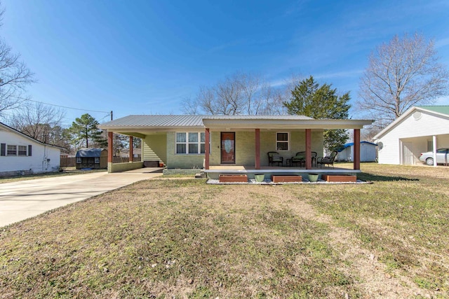 view of front of property with a front lawn, metal roof, and concrete driveway