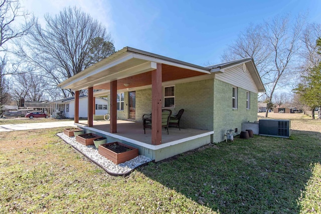 rear view of house featuring a yard, central AC, brick siding, and a patio