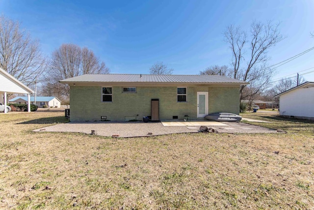 rear view of property with metal roof, brick siding, a lawn, and a patio area