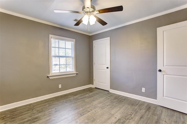 unfurnished room with ceiling fan, wood finished floors, visible vents, baseboards, and crown molding