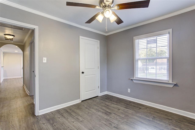 unfurnished bedroom with ornamental molding, arched walkways, attic access, and wood finished floors