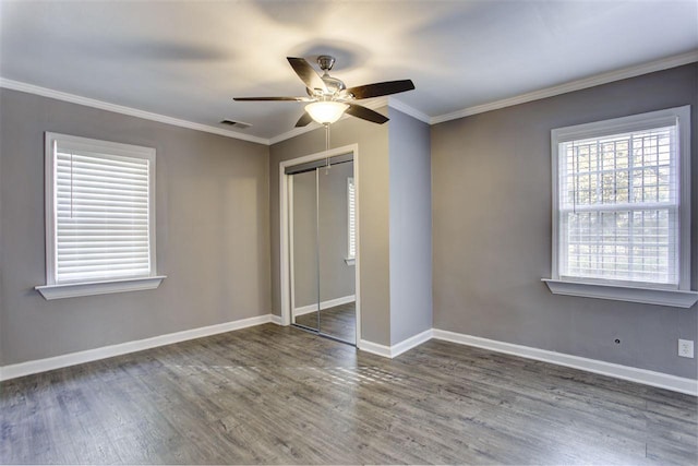 unfurnished bedroom with baseboards, a closet, ornamental molding, and wood finished floors