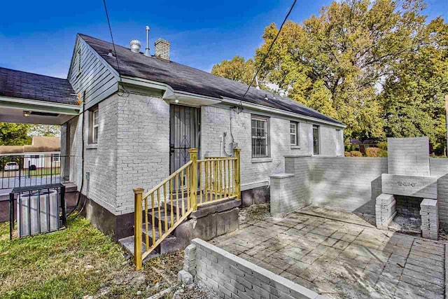 rear view of house with a patio area, a chimney, fence, and brick siding