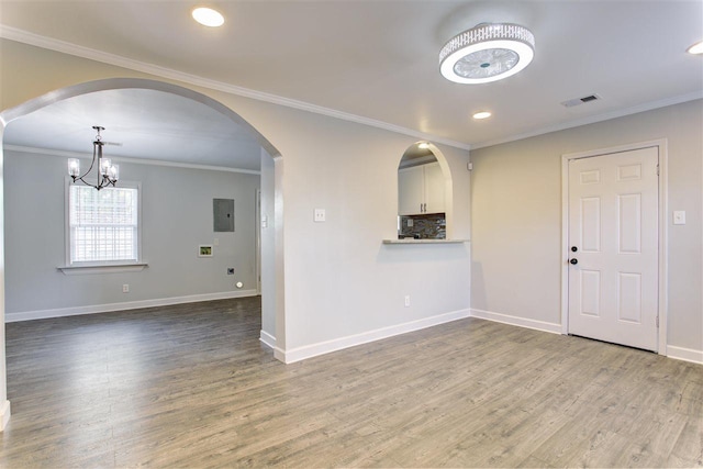 spare room with crown molding, visible vents, wood finished floors, electric panel, and baseboards