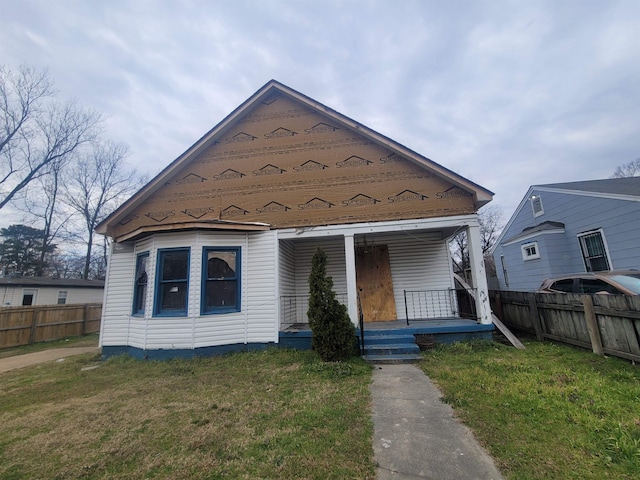 view of front of property featuring a porch, fence, and a front lawn