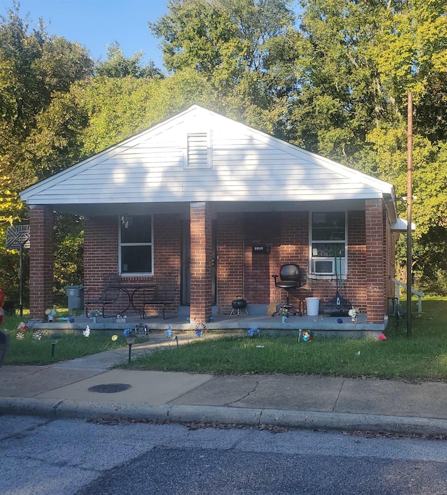 bungalow with brick siding, a porch, and cooling unit