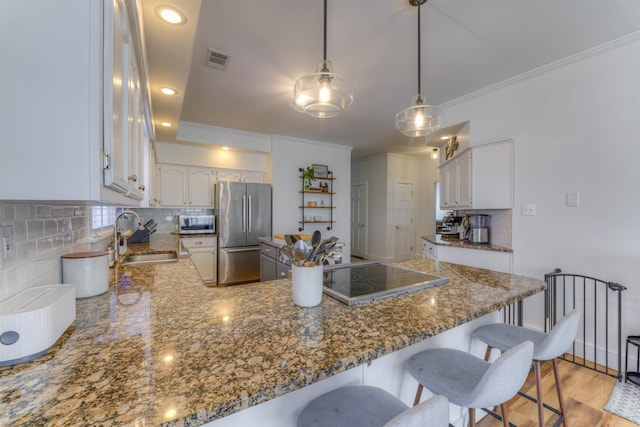 kitchen with visible vents, appliances with stainless steel finishes, ornamental molding, a sink, and a peninsula