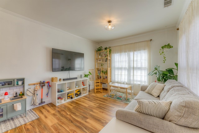 living area featuring visible vents, wood finished floors, and ornamental molding