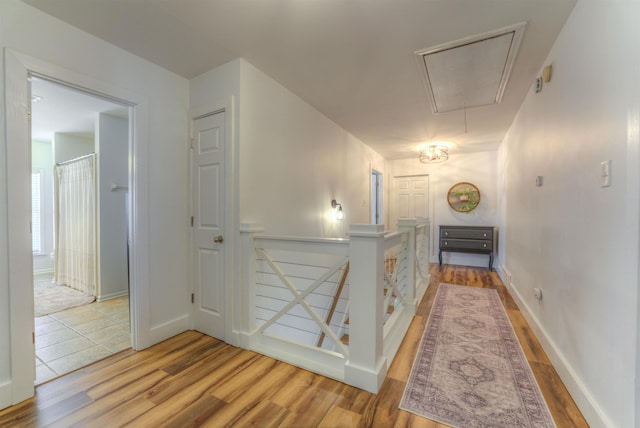 corridor featuring attic access, baseboards, an upstairs landing, and wood finished floors