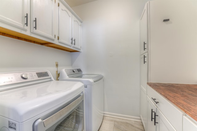 washroom featuring washing machine and dryer, cabinet space, and baseboards