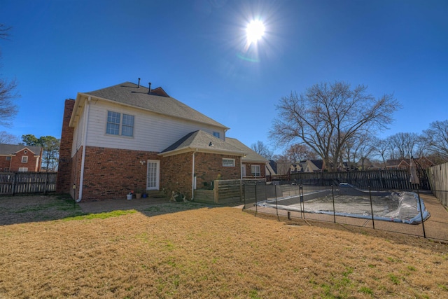 rear view of property with brick siding, a fenced backyard, and a yard