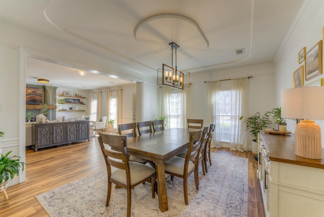 dining area featuring a chandelier, light wood finished floors, and crown molding