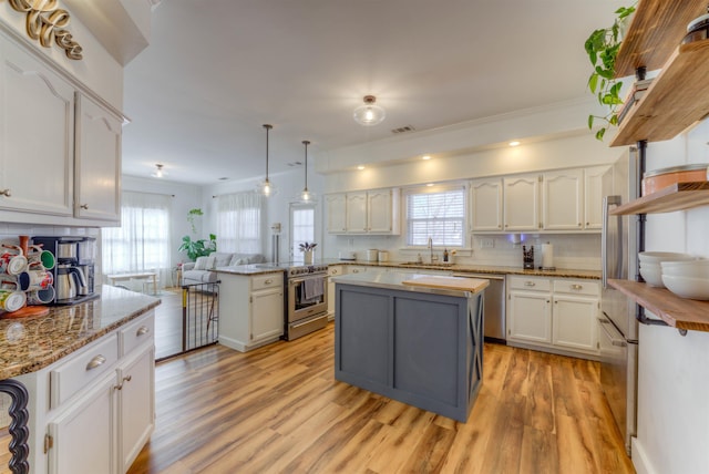 kitchen featuring stainless steel appliances, white cabinetry, a peninsula, and light wood finished floors