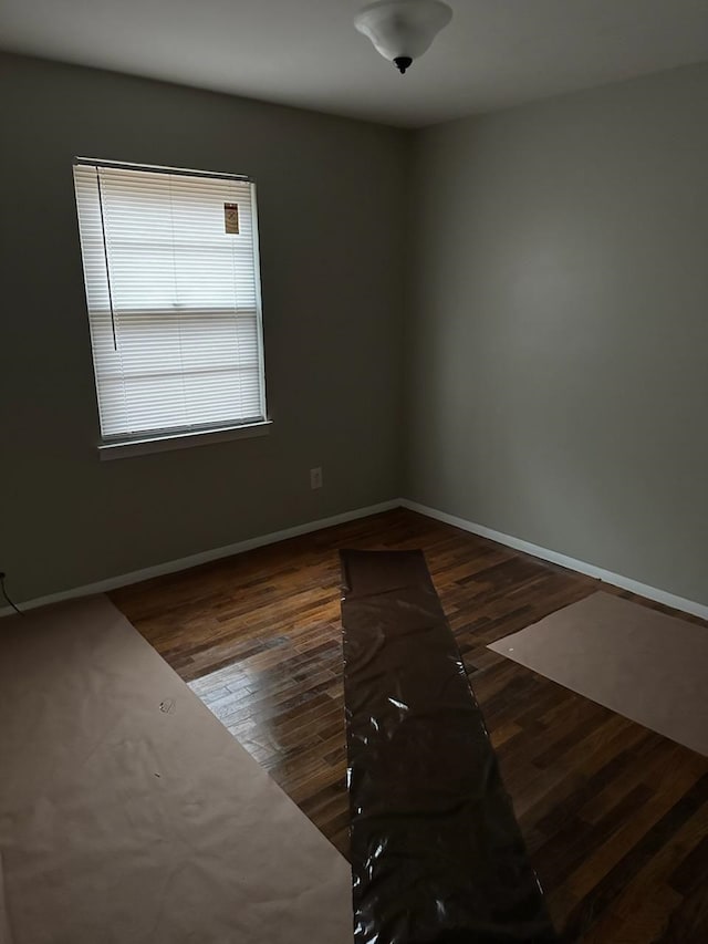 spare room with dark wood-style flooring and baseboards