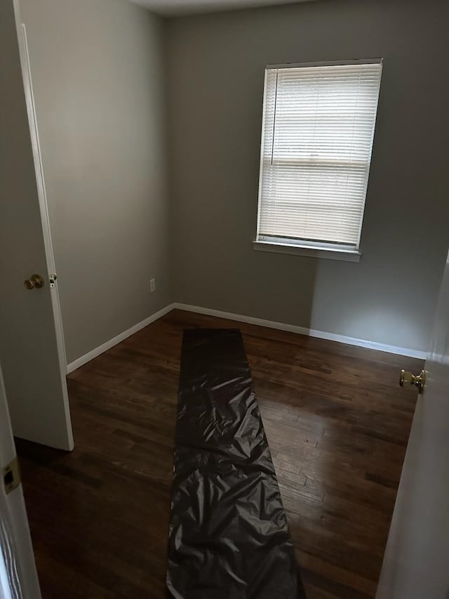 unfurnished room with baseboards and wood finished floors