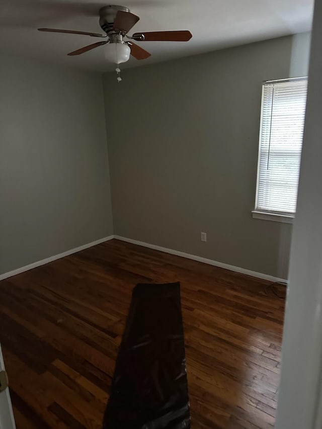 spare room featuring wood finished floors, a ceiling fan, and baseboards