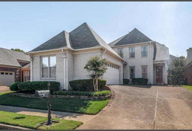 view of front of property with a front yard, brick siding, driveway, and an attached garage