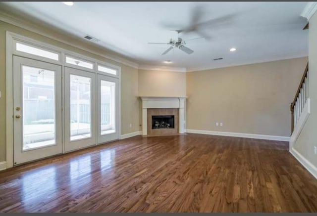 unfurnished living room featuring ornamental molding, a tiled fireplace, wood finished floors, and baseboards