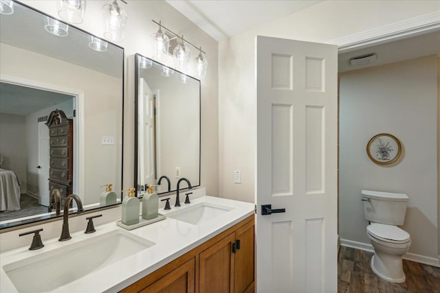 bathroom featuring double vanity, wood finished floors, a sink, and toilet