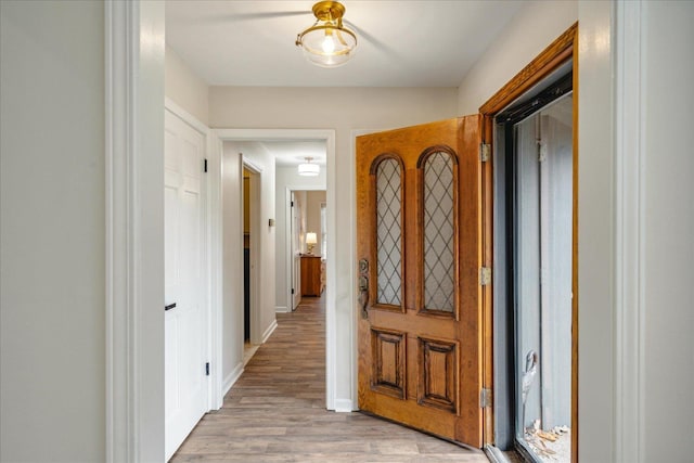 hallway featuring baseboards and light wood finished floors