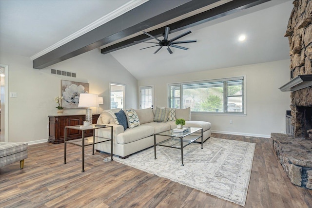 living area featuring baseboards, visible vents, wood finished floors, a fireplace, and beam ceiling