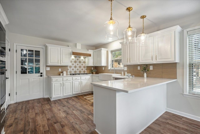 kitchen with dark wood finished floors, stainless steel gas cooktop, custom exhaust hood, white cabinetry, and a sink