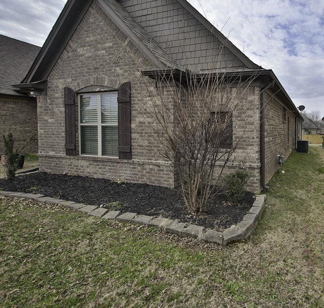 view of side of home with a yard, cooling unit, and brick siding