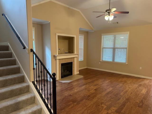 unfurnished living room with lofted ceiling, ceiling fan, stairway, wood finished floors, and a fireplace