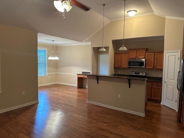 kitchen featuring electric stove, brown cabinets, stainless steel microwave, dark countertops, and a kitchen bar