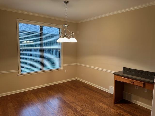 unfurnished dining area featuring ornamental molding, dark wood finished floors, and baseboards