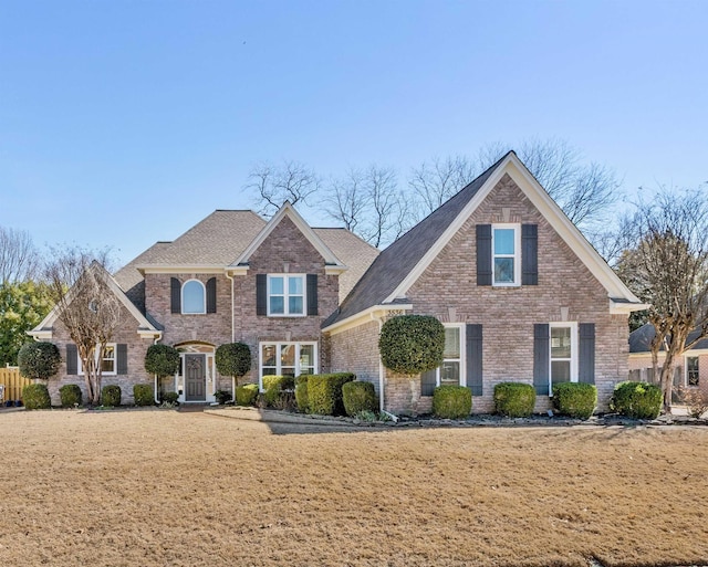 traditional home featuring brick siding and a front lawn