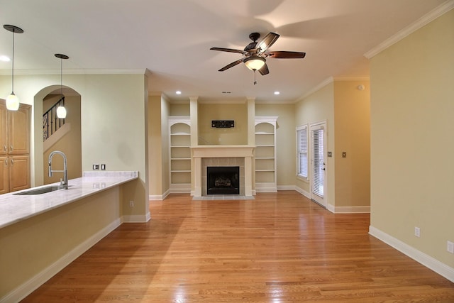 unfurnished living room with light wood-type flooring, baseboards, a sink, and a tile fireplace