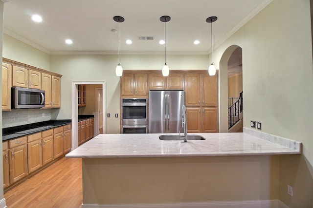 kitchen featuring appliances with stainless steel finishes, tasteful backsplash, a sink, and light stone countertops