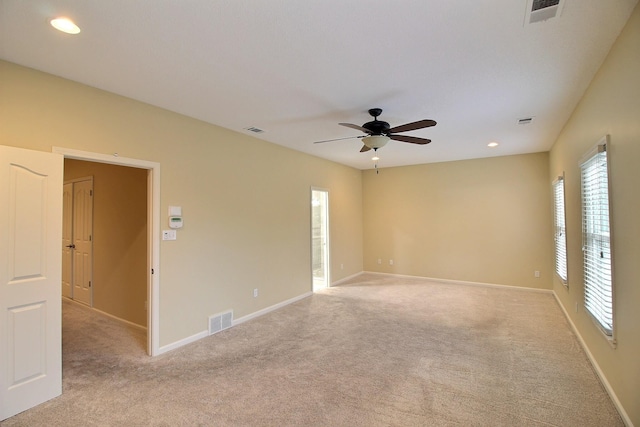 spare room featuring light colored carpet, visible vents, and baseboards