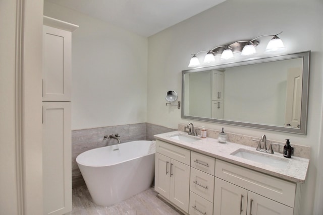 full bathroom with double vanity, wood finished floors, a soaking tub, and a sink