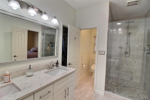 bathroom with double vanity, visible vents, toilet, a shower stall, and a sink